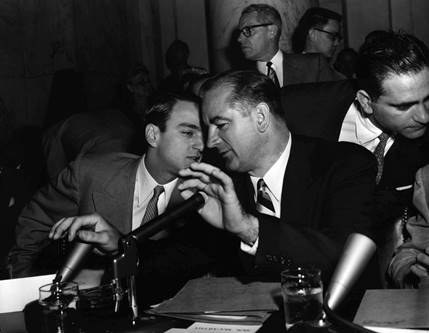 U.S. Senator Joseph McCarthy (covering microphones) during an investigation into communist infiltration of the government.