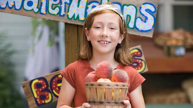 A young person holds a basket of peaches.