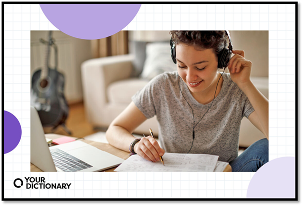 student with headphones writing essay outline on paper